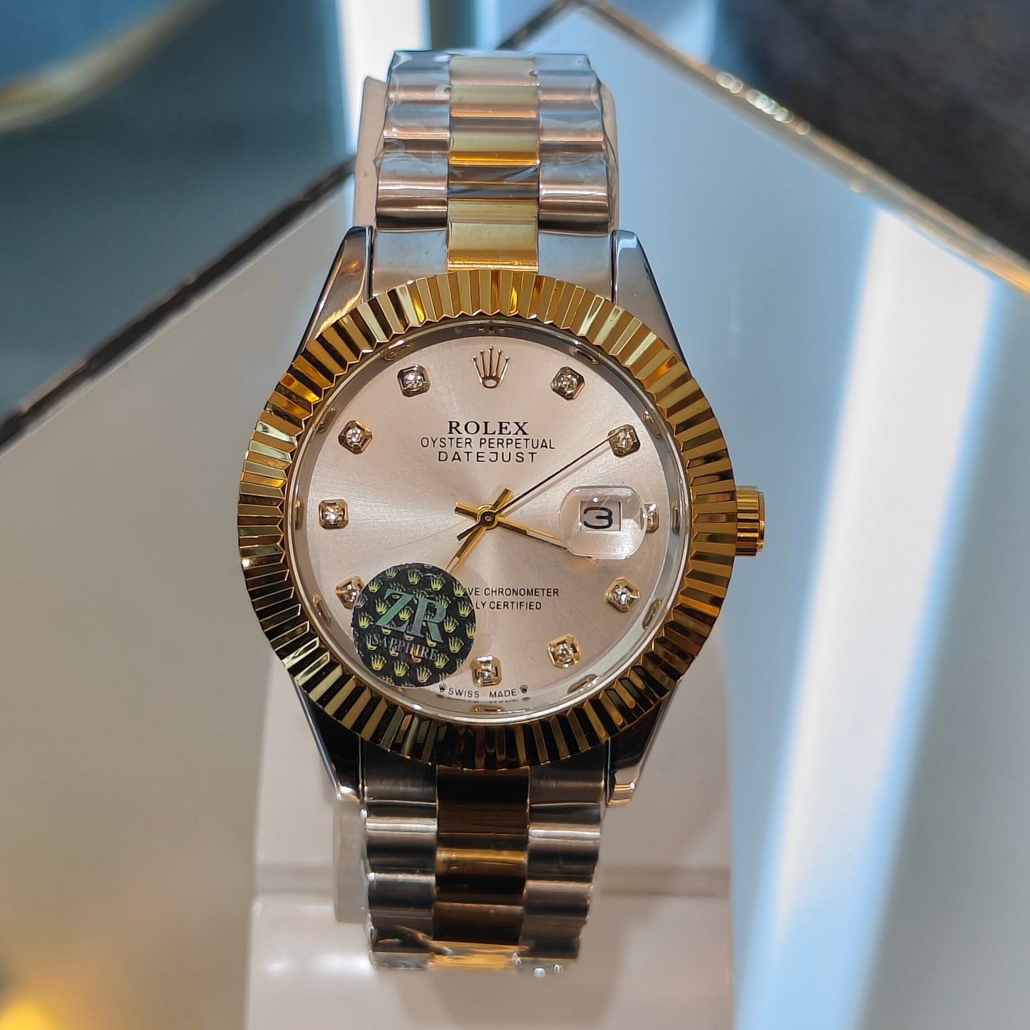 Gold and silver watch on a display stand with a blurred background