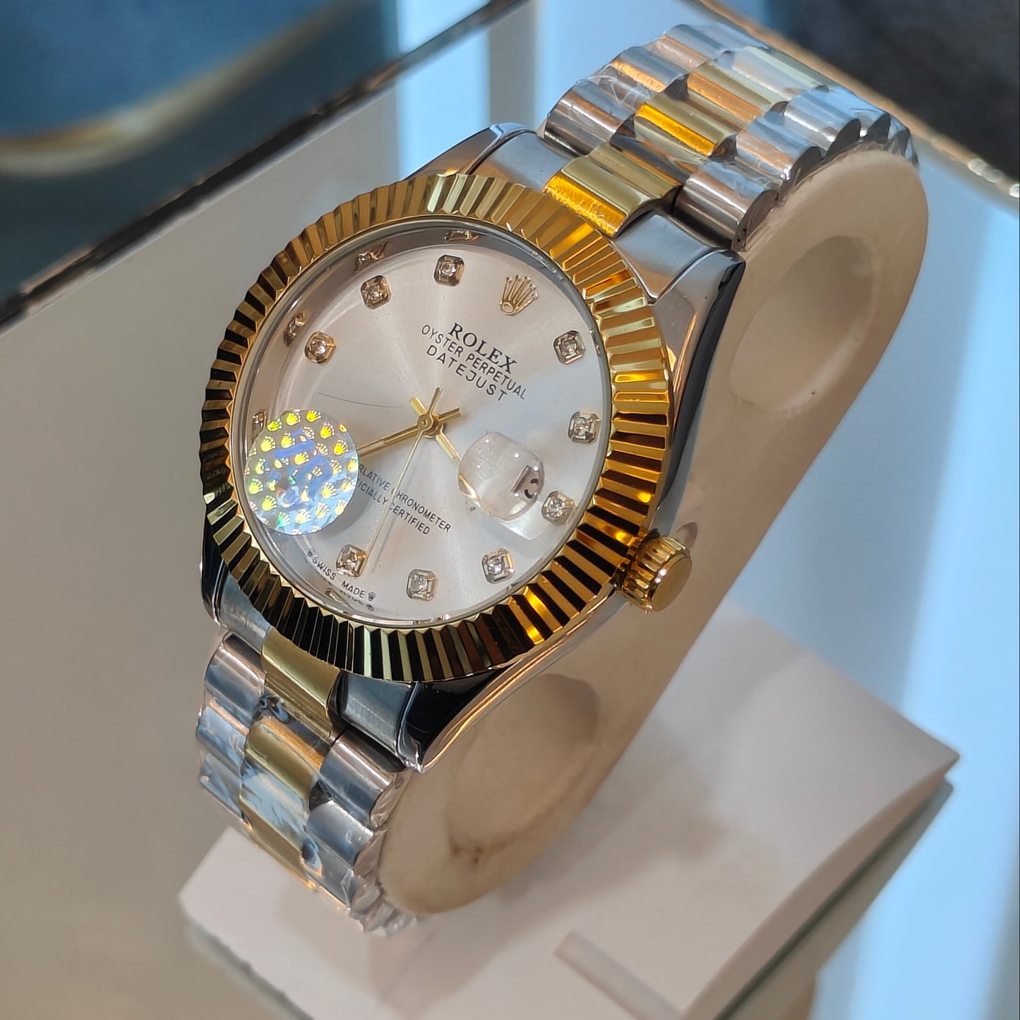 Gold and silver watch on a display stand with a blurred background