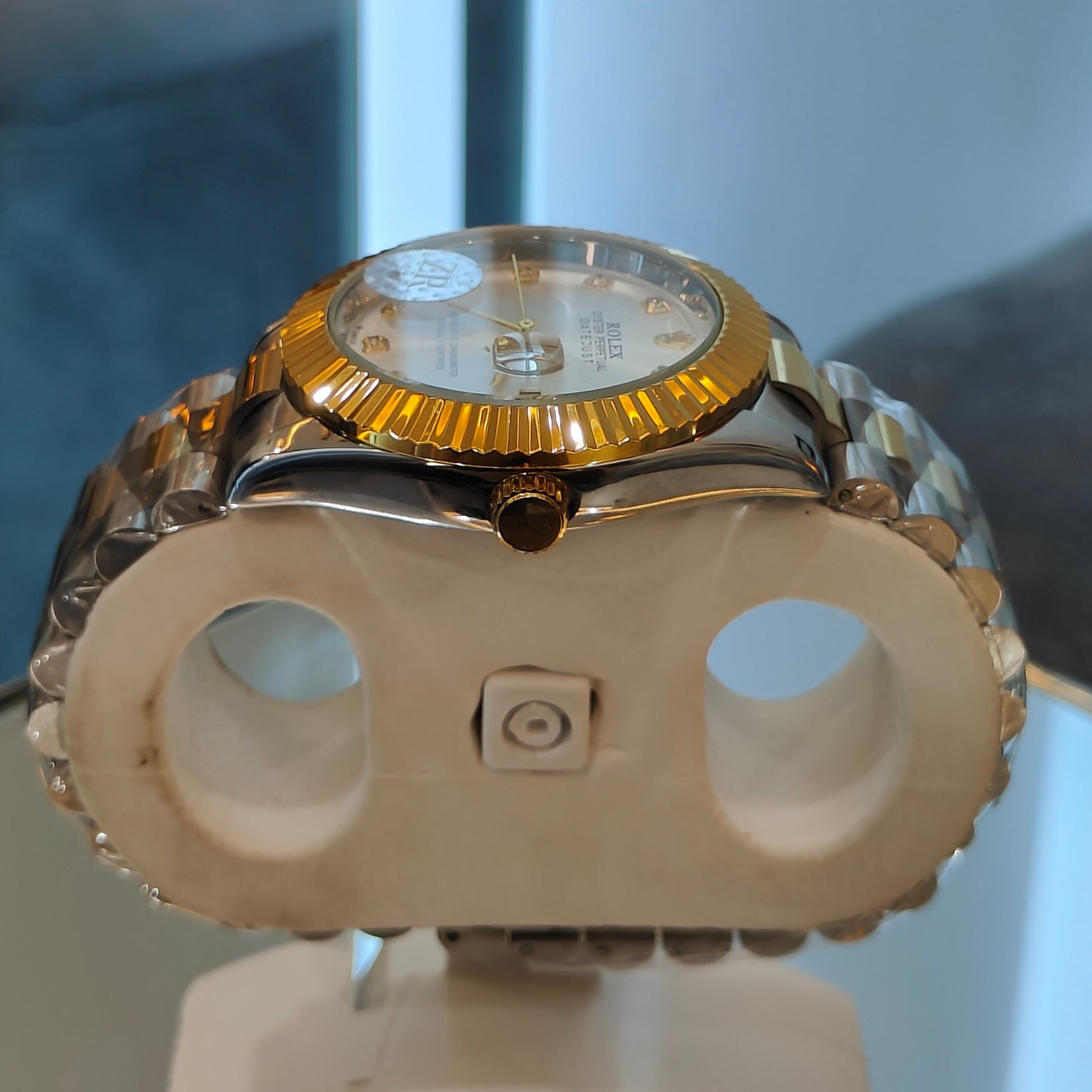 Gold watch on a display stand with a blurred background